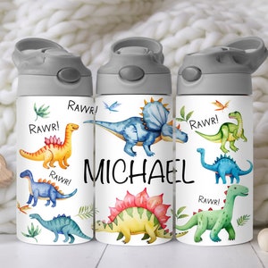 May include: Three white water bottles with grey lids and a dinosaur theme. The bottles have a watercolor design of dinosaurs with the word "RAWR!" and the name "MICHAEL" on the middle bottle.