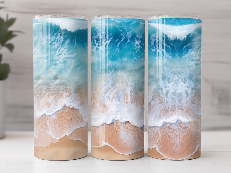 May include: Three stainless steel tumblers with a beach scene design. The tumblers feature a blue ocean with white waves crashing on a sandy beach.
