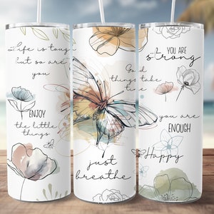 May include: Three stainless steel tumblers with inspirational quotes and watercolor floral and butterfly designs. The quotes are "Life is tough but so are you", "Good things take time, just breathe", and "You are strong, you are enough, Happy".
