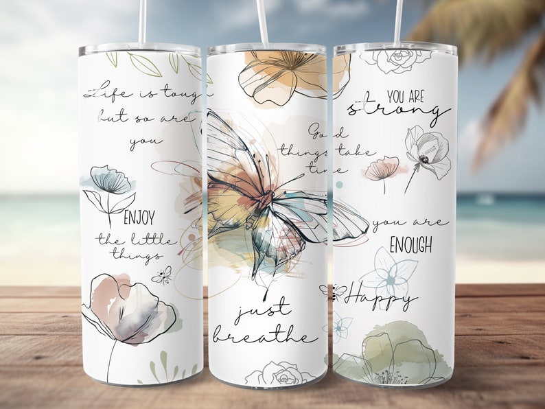 May include: Three stainless steel tumblers with inspirational quotes and watercolor floral and butterfly designs. The quotes are "Life is tough but so are you", "Good things take time, just breathe", and "You are strong, you are enough, Happy".