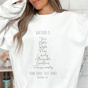 May include: White sweatshirt with the text "WHATEVER IS" followed by a list of words: "True, Noble, Right, Pure, Lovely, Admirable, Excellent, Praiseworthy". The text "THINK ABOUT SUCH THINGS" is below the list, followed by "PHILIPPIANS 4:8".