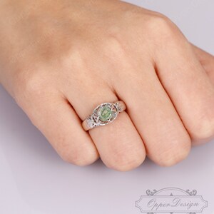 May include: A silver ring with a green gemstone set in a delicate filigree design.