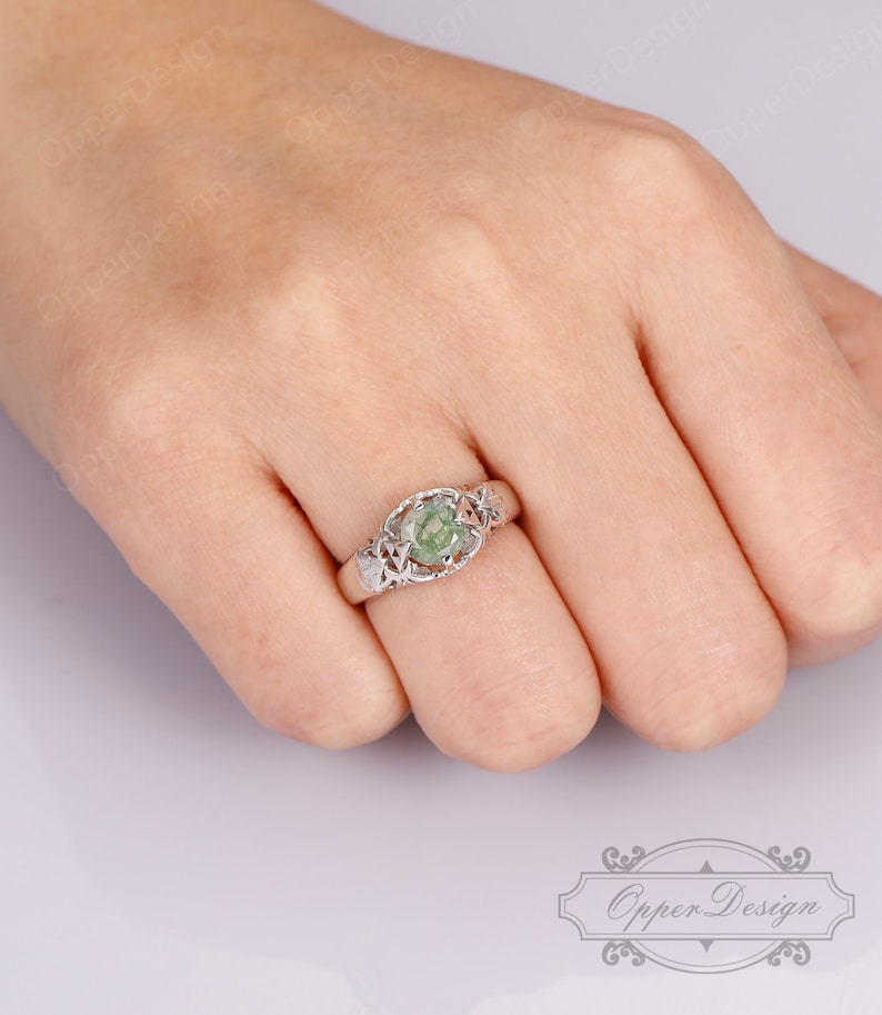 May include: A silver ring with a green gemstone set in a delicate filigree design.