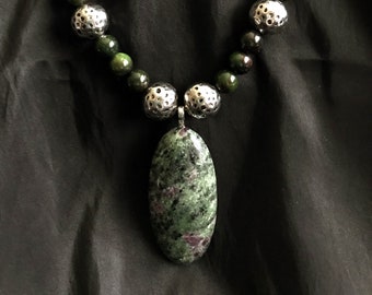 Ruby Zoisite oval pendant with Ruby Zoisite, hammered metal, and seed beads, toggle clasp
