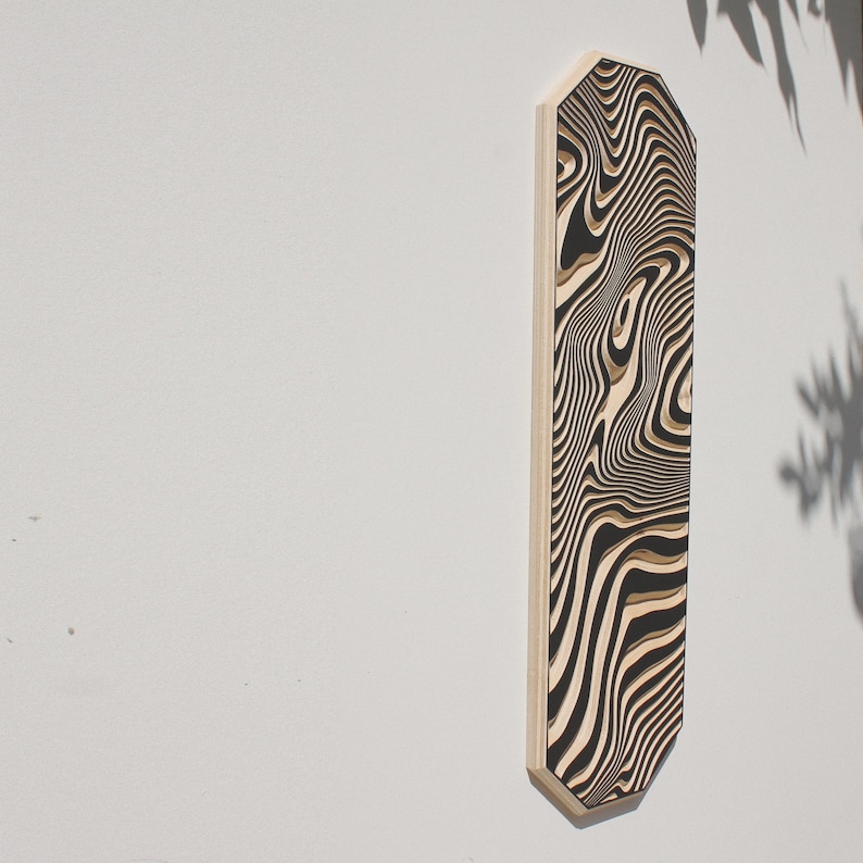 May include: A black and white abstract wood wall art piece with a wavy pattern. The art is mounted on a white wall.