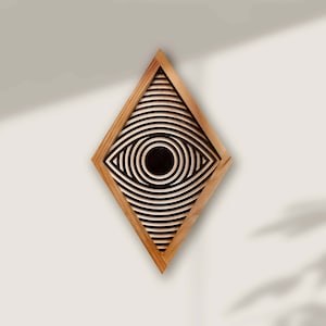 May include: A wooden wall decor in the shape of a diamond with a black and white eye design inside.