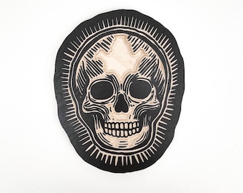 木版画で彫刻された小さな頭蓋骨の壁掛け。