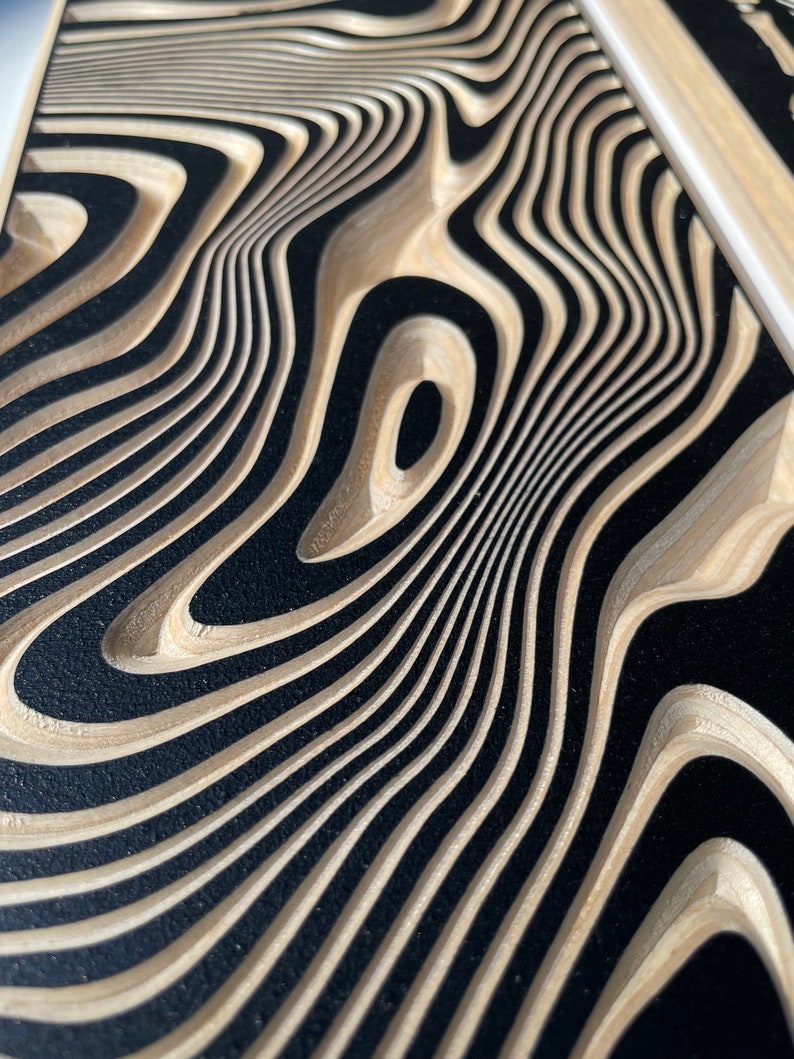 May include: Close-up of a wood panel with a black and brown wavy pattern. The pattern is created by layers of wood that have been cut and layered to create a 3D effect.