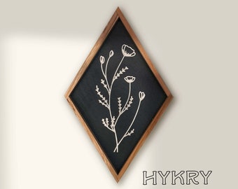May include: A black diamond-shaped wooden frame with a white floral design on a black background. The frame has a dark wood finish.