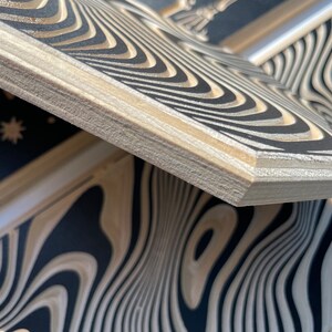 May include: Close-up of a wooden box with a black and white wavy pattern. The box is made of plywood and has a natural wood finish.