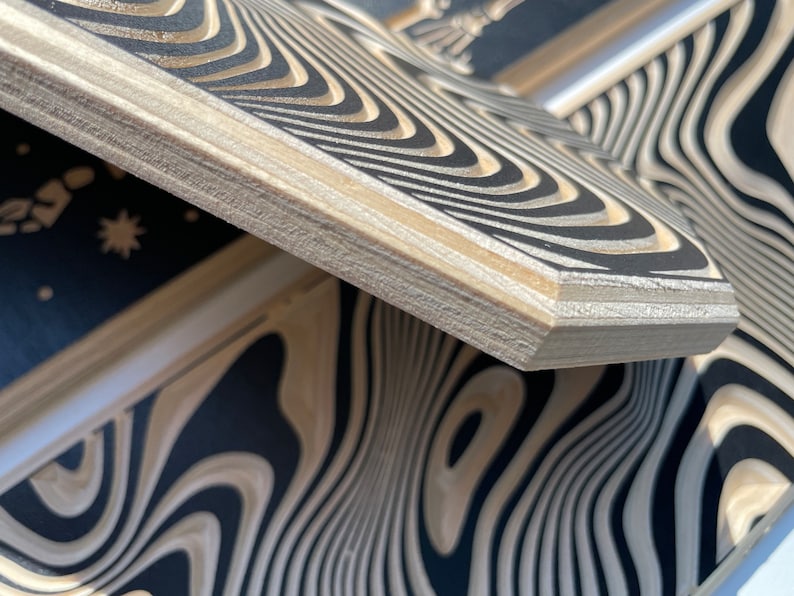 May include: Close-up of a wooden box with a black and white wavy pattern. The box is made of plywood and has a natural wood finish.