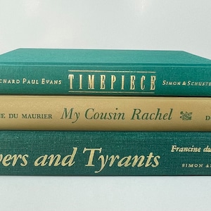 May include: A stack of three hardcover books with green and tan covers. The top book is titled "Timepiece" by Richard Paul Evans. The middle book is titled "My Cousin Rachel" by Daphne du Maurier. The bottom book is titled "Lovers and Tyrants" by Francine du Plessix Gray.