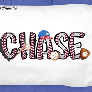 May include: White pillowcase with the name "CHASE" in black letters with a baseball theme. The letters are decorated with a red and white baseball stitching pattern. There is a baseball player silhouette, baseballs, bats, and a baseball cap with a star on it.