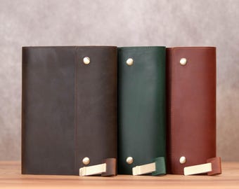 May include: Three leather-bound journals in brown, green, and red, each with a gold metal closure.