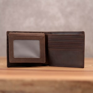 Puede incluir: Una cartera de cuero marr&oacute;n con m&uacute;ltiples ranuras para tarjetas y una ventana de identificaci&oacute;n transparente.