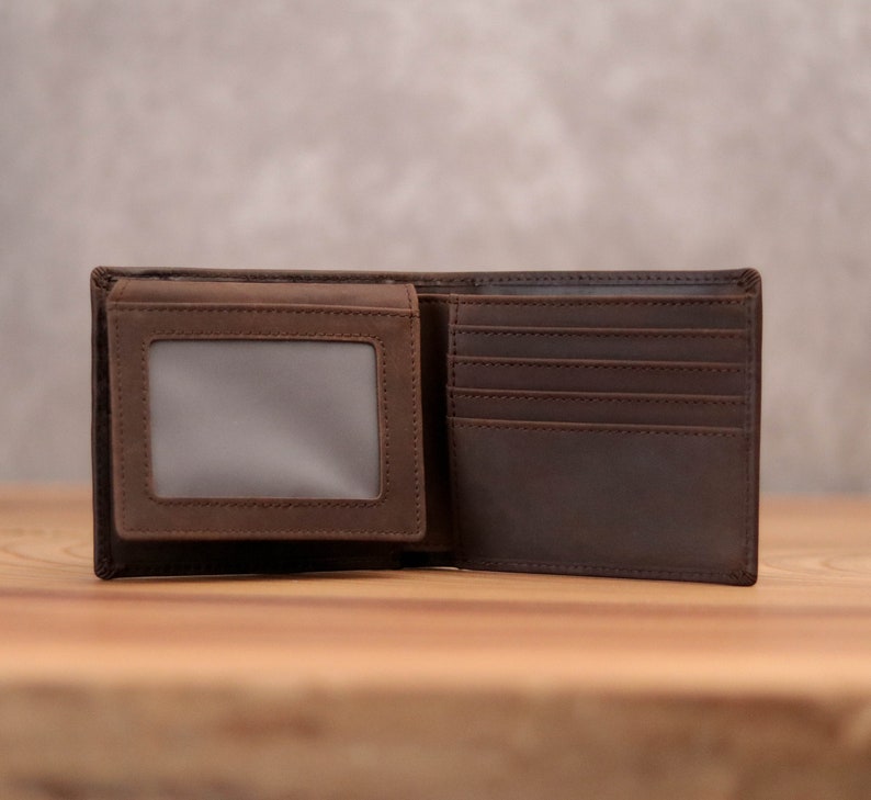 Puede incluir: Una cartera de cuero marr&oacute;n con m&uacute;ltiples ranuras para tarjetas y una ventana de identificaci&oacute;n transparente.
