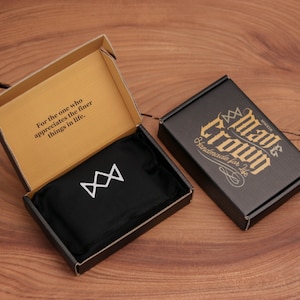 Puede incluir: Una caja negra con un logotipo de corona blanca y el texto "Para el que aprecia las cosas m&aacute;s finas de la vida." La caja est&aacute; abierta y una bolsa negra con un logotipo de corona blanca est&aacute; dentro. Una segunda caja negra est&aacute; cerrada con el texto "Made for You Crown" en letras doradas.