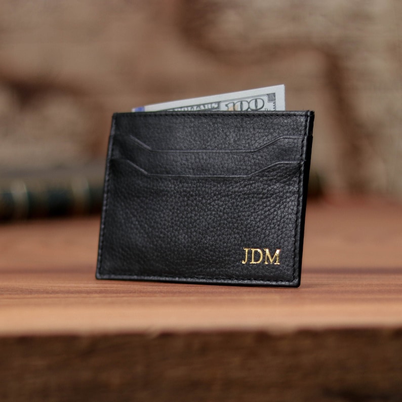 May include: Black leather card holder with a gold embossed monogram "JDM".