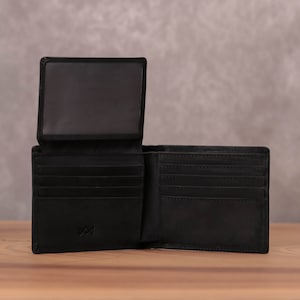 Puede incluir: Una cartera de cuero negra con m&uacute;ltiples ranuras para tarjetas y un portafolios. La cartera tiene una peque&ntilde;a ventana para mostrar una identificaci&oacute;n.