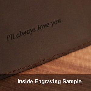 Puede incluir: Primer plano de una cartera de cuero marr&oacute;n con la inscripci&oacute;n "I'll always love you." en el interior. La cartera est&aacute; sobre una superficie de madera. Muestra de grabado interior.
