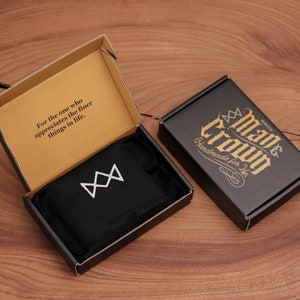 May include: An open cardboard box with the text "For the one who appreciates the finer things in life." A black box with gold text that reads "Mave Crown Handmade for Life" is next to it. Inside the open box is a black pouch with a white geometric design.