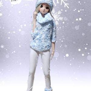 May include: A doll is wearing a light blue and white textured sweater, beanie, and leg warmers, with a matching infinity scarf. The doll is also wearing white trousers and brown boots. The image text reads "Snow Bunny".