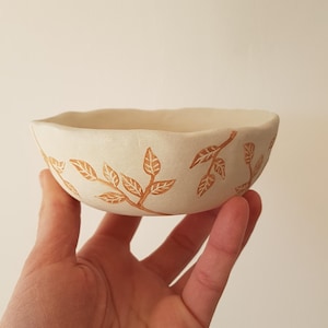 Op de afbeelding: Een set van drie keramische nestkommen. De grootste kom is lichtblauw, de middelste kom is wit en de kleinste kom is donkerder blauw. Elke kom heeft een gladde, glanzende afwerking.