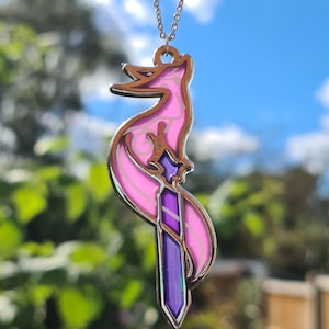 May include: A silver chain necklace with a pink and purple enamel pendant featuring a stylized fox holding a sword.