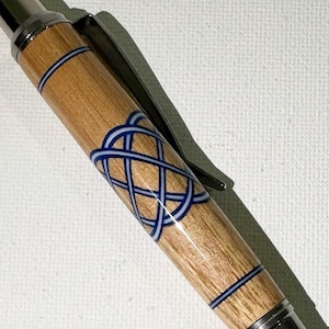 May include: A wooden pen with a silver clip and a blue and white Celtic knot design.