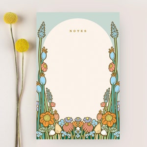 May include: A light blue notepad with a floral border. The border features blue, orange, and pink flowers. The notepad has the word "NOTES" printed in gold at the top.