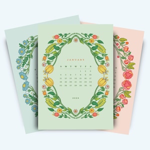 May include: Three floral calendars for January 2026. The calendars feature a botanical design with a central oval frame of flowers and leaves. The calendars are in pastel colors: light blue, green, and pink.