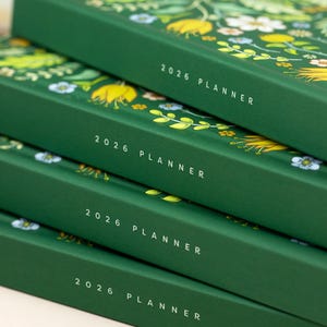 Stack of 2026 hardcover calendar planner books featuring green bright floral cover design
