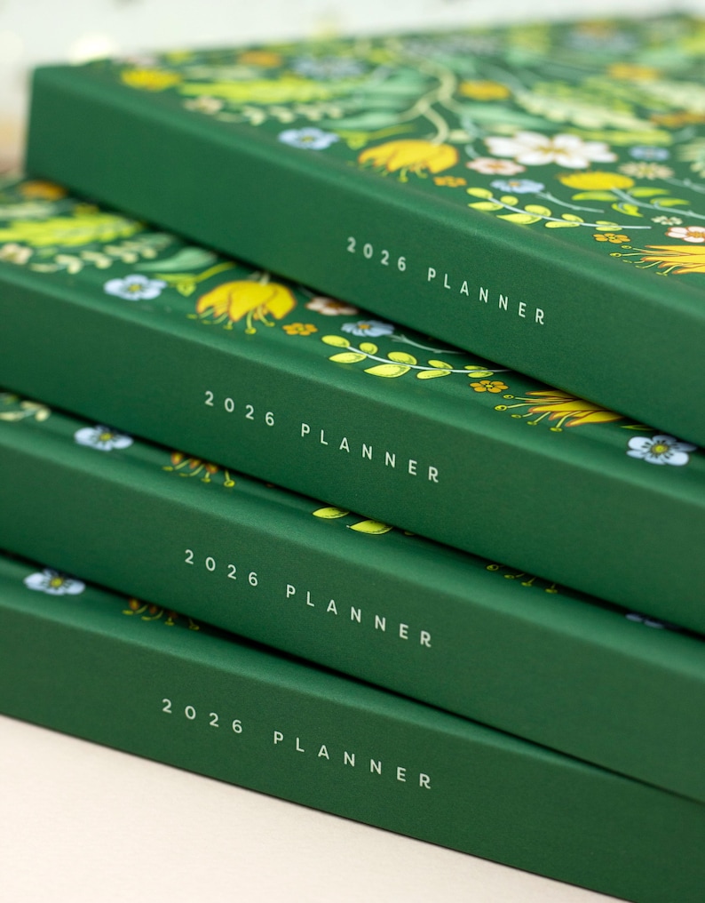 Stack of 2026 hardcover calendar planner books featuring green bright floral cover design