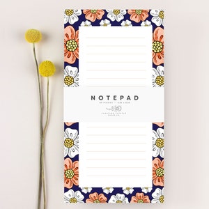 May include: A notepad with a floral design featuring white and peach flowers on a navy blue background. The notepad has 85 pages and measures 4.25 x 8.25 inches. The text "NOTEPAD" is printed in white at the top of the notepad. The text "FLOATING THISTLE PAPER CO." is printed in white at the bottom of the notepad.