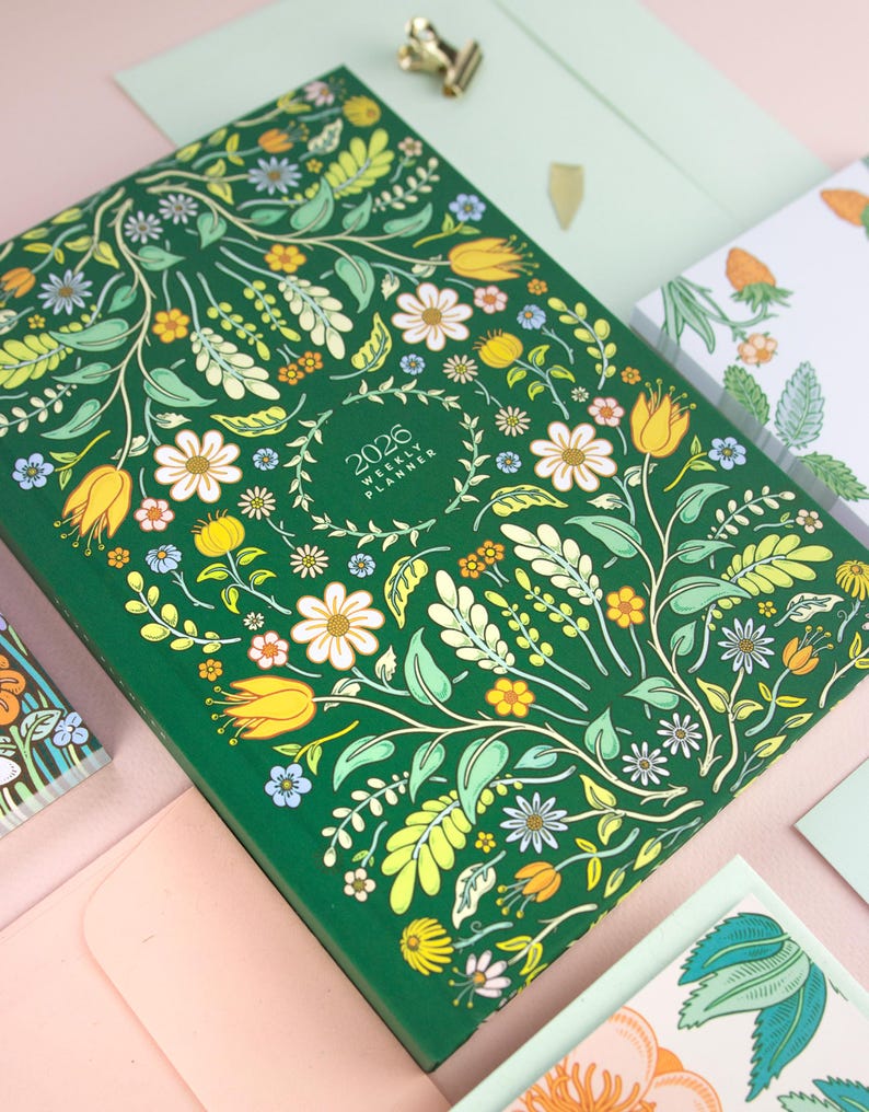 Hardcover yearly planner with bright and colorful cover design featuring folk, cottagecore style artwork.