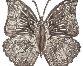 May include: A silver metal butterfly wall decoration with intricate cutouts and a textured finish. The butterfly has a detailed body and wings with a hammered metal look. The words "TEAM HAPPY PIERCE" are engraved on the bottom of the butterfly.