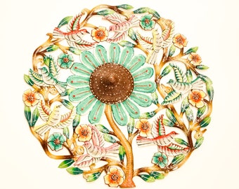 May include: A circular metal wall art piece depicting a stylized tree with a large green flower in the center. The tree has brown branches with green leaves and colorful birds. The flower has a brown center and white petals with green accents.