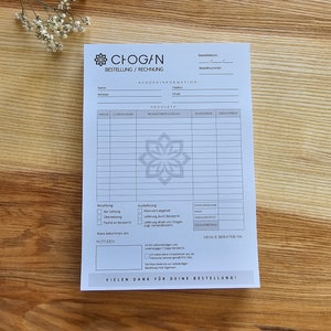 May include: A white order form with the text "CHOGAN BESTELLUNG/RECHNUNG" at the top. The form includes sections for customer information, product details, payment options, and delivery preferences. It also includes a section for notes and a space for the customer's consultant's information.