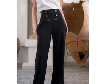 May include: Black high-waisted wide-leg pants with large, dark buttons. The pants have a tailored fit and a classic design. The model is wearing a white tank top. The pants are made of a smooth, dark fabric.