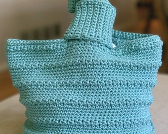 May include: A teal blue crocheted tote bag with a knotted handle.