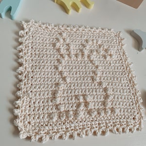 Puede incluir: Un pa&ntilde;o de cocina cuadrado de color crema tejido a crochet con un patr&oacute;n texturizado. El pa&ntilde;o de cocina tiene un borde festoneado.