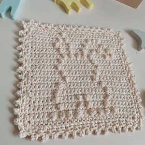 Puede incluir: Un pa&ntilde;o de cocina cuadrado de color crema tejido a crochet con un patr&oacute;n texturizado. El pa&ntilde;o de cocina tiene un borde festoneado.