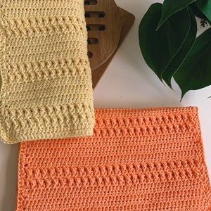 K&ouml;nnte beinhalten: Zwei geh&auml;kelte Geschirrt&uuml;cher, eines gelb und eines orange, mit einem strukturierten Muster. Die Geschirrt&uuml;cher sind mit einem einfachen Stich gearbeitet und perfekt f&uuml;r den t&auml;glichen Gebrauch.