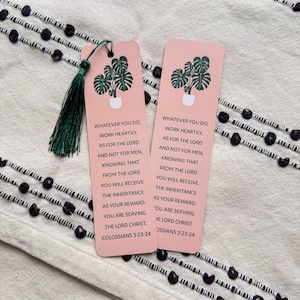 May include: Two pink bookmarks with a green plant illustration and a tassel. The bookmarks feature the Bible verse Colossians 3:23-24, which reads "Whatever you do, work heartily, as for the Lord and not for men, knowing that from the Lord you will receive the inheritance as your reward. You are serving the Lord Christ."