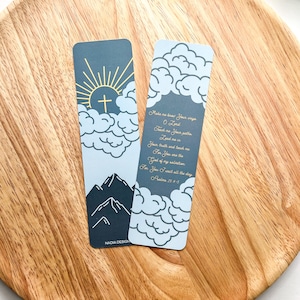 Op de afbeelding: Twee rechthoekige bladwijzers met een lichtblauw en donkerblauw ontwerp. Eén bladwijzer heeft een zon, kruis en berg afbeelding. De andere bladwijzer heeft een citaat uit Psalm 25:4-5. De bladwijzers liggen op een houten dienblad.