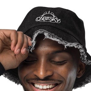 May include: A black bucket hat with a frayed edge and the text "DAB SKY" embroidered in white on the front.