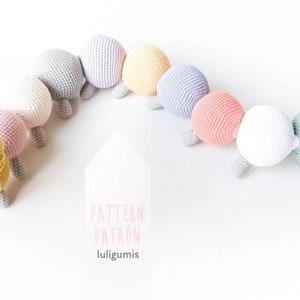 Puede incluir: Un juguete de oruga de crochet con una cabeza amarilla y un cuerpo colorido. La oruga está enroscada en forma de círculo. El juguete está hecho de hilo suave y tiene una expresión amigable.