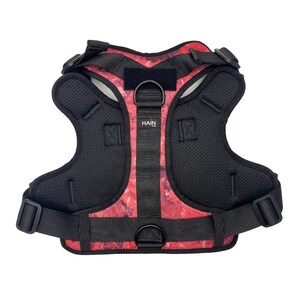 May include: Red and black dog harness with a mesh lining and the word "HAIN" printed on the front.