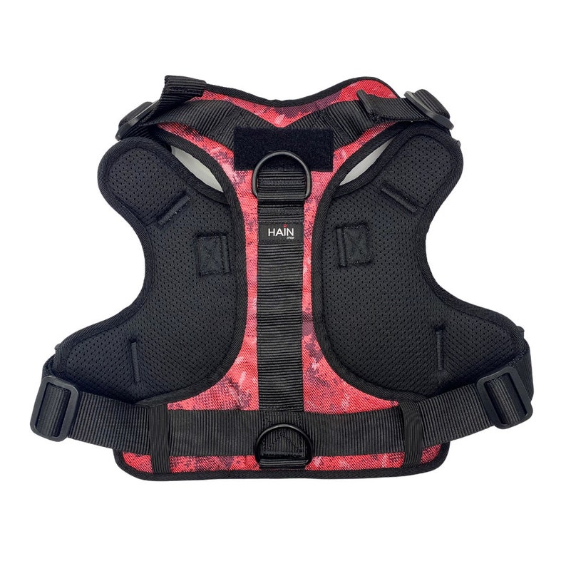 May include: Red and black dog harness with a mesh lining and the word "HAIN" printed on the front.