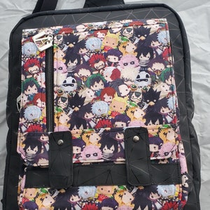 May include: Black backpack with a geometric pattern and a front pocket featuring a colourful print of cartoon characters.